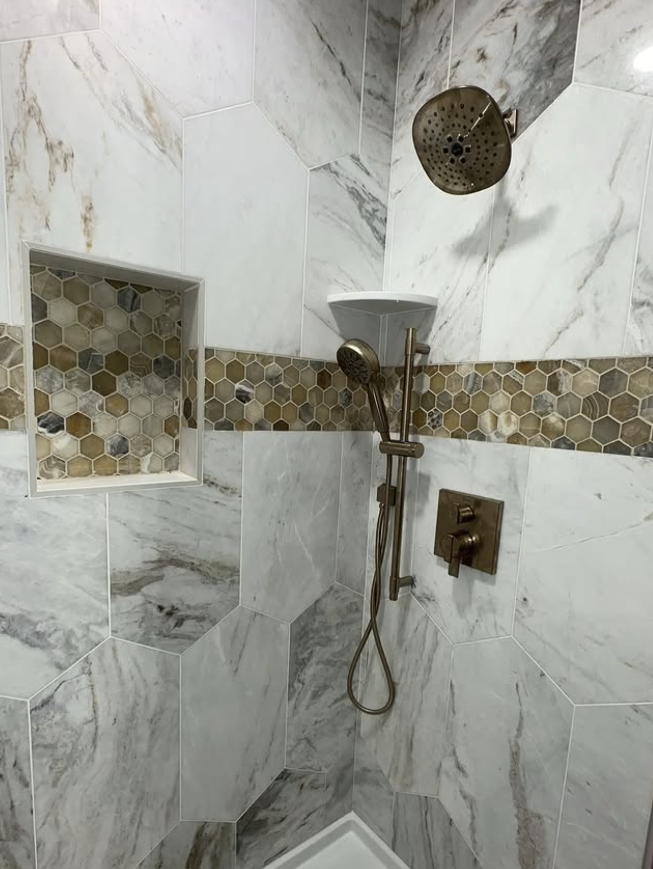 Marble hex tile shower with brass fixtures in South River, NJ