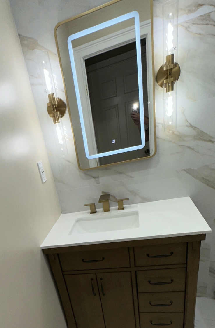 Wood vanity with brass sconces and LED mirror after bathroom remodel in Parlin, NJ